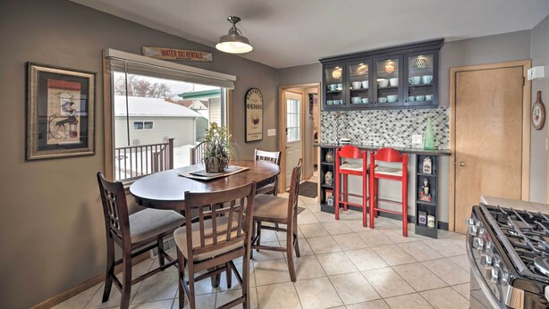 A dining area with a wooden table and chairs, a kitchen with cabinets and a stove, and a sign above the door reading "Water Ski Rentals".