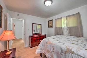 Une chambre à coucher avec un lit, une commode, un miroir et une lampe.