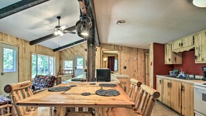 A rustic kitchen with wooden cabinetry, a large wooden table, and a ceiling fan. - Rustic Mcgregor Retreat on Big Sandy Lake! (McGregor)