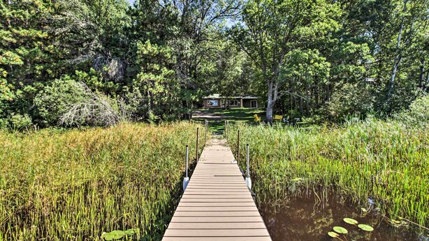 A wooden dock leading to a cabin surrounded by dense forest and water. - Rustic Mcgregor Retreat on Big Sandy Lake! (McGregor)