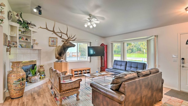 Een woonkamer met een open haard, een groot decoratiehoofd van een hert, een televisie en een leren bank.