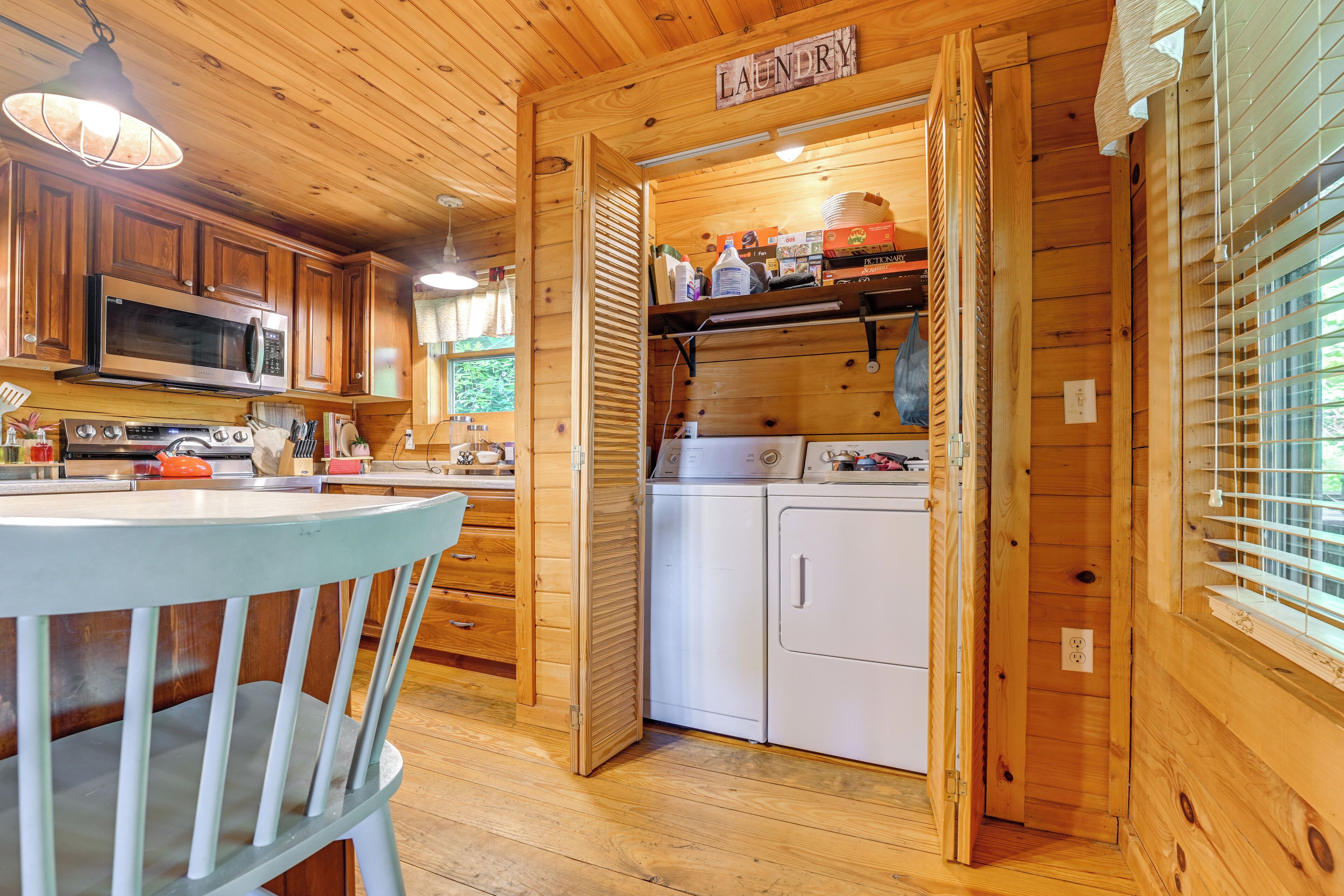 A wooden cabin interior with a kitchen area featuring a microwave, stove, and cabinets.