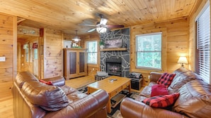 A cozy cabin interior with a stone fireplace, leather sofas, wooden walls, and a ceiling fan. - Near Hikes & River! Pet-friendly Bryson City Haven (Bryson City)