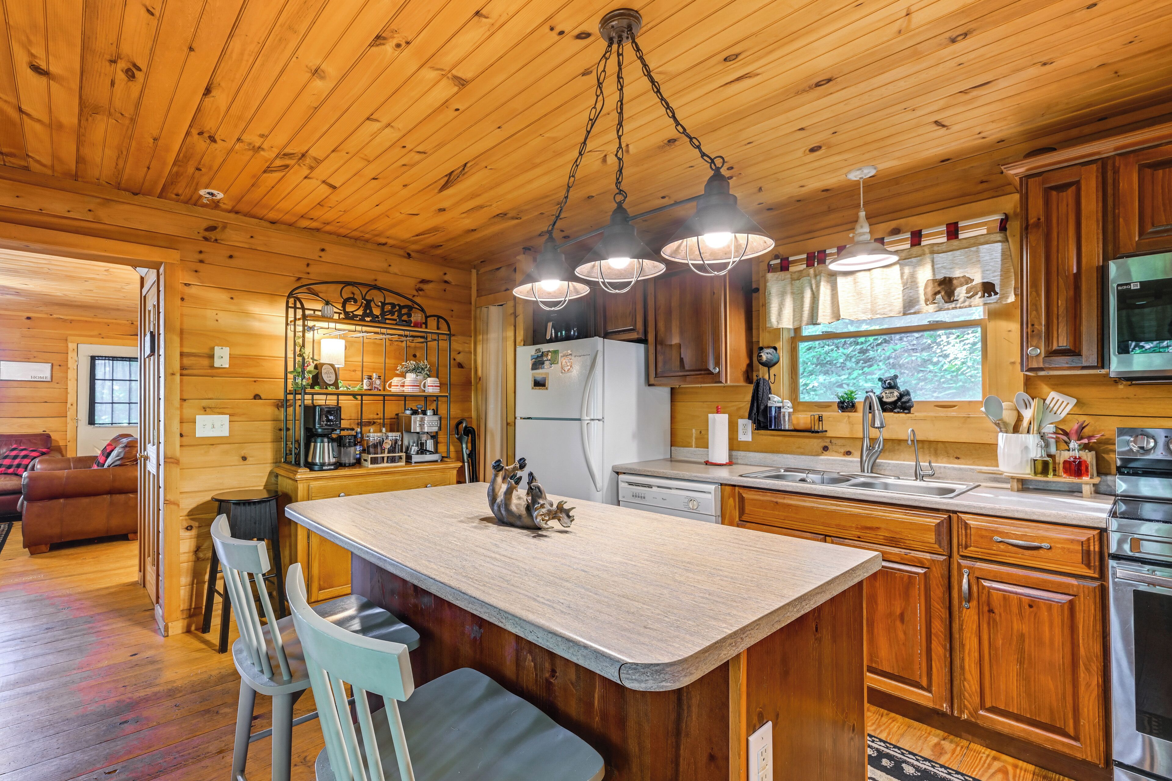 A wooden cabin interior with a kitchen featuring a central island, bar area, and a dining space with chairs.