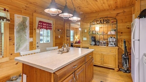 A wooden cabin interior with a kitchen area featuring a large island, wooden cabinets, and a coffee station. - Near Hikes & River! Pet-friendly Bryson City Haven (Bryson City)