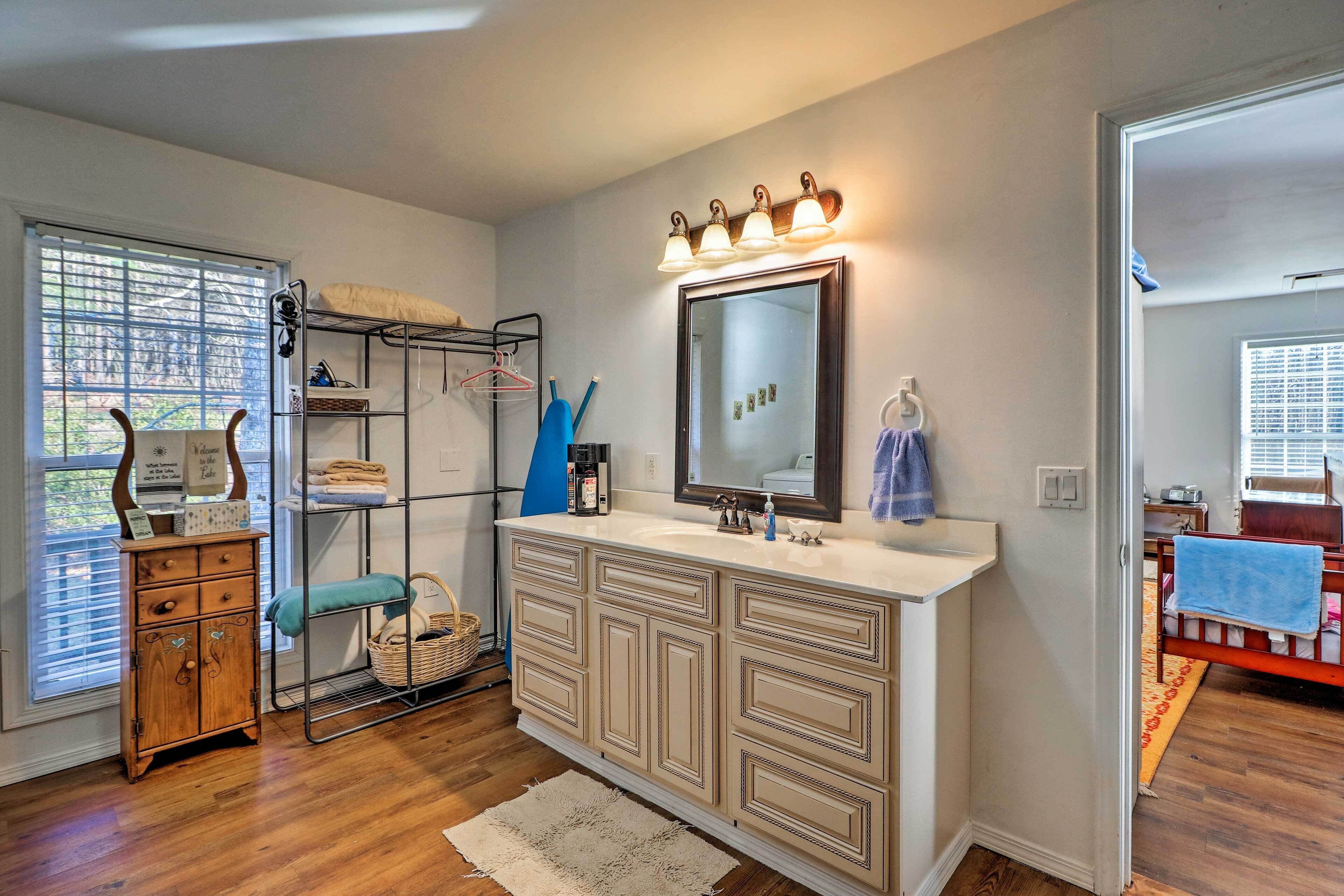 A bathroom with a vanity, a mirror, and a shower area.