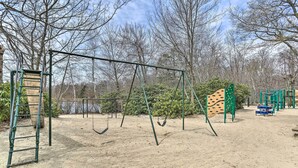 Un parque infantil con columpios, una estructura para escalar y un arenero.