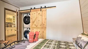 Un dormitorio pequeño con cama, lavadora y armario corredero.