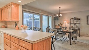 A kitchen with wooden cabinets, a large island, and a dining area with metal chairs and a table. - Lakefront Townhome w/ View in Hot Springs Village! (Hot Springs Village)