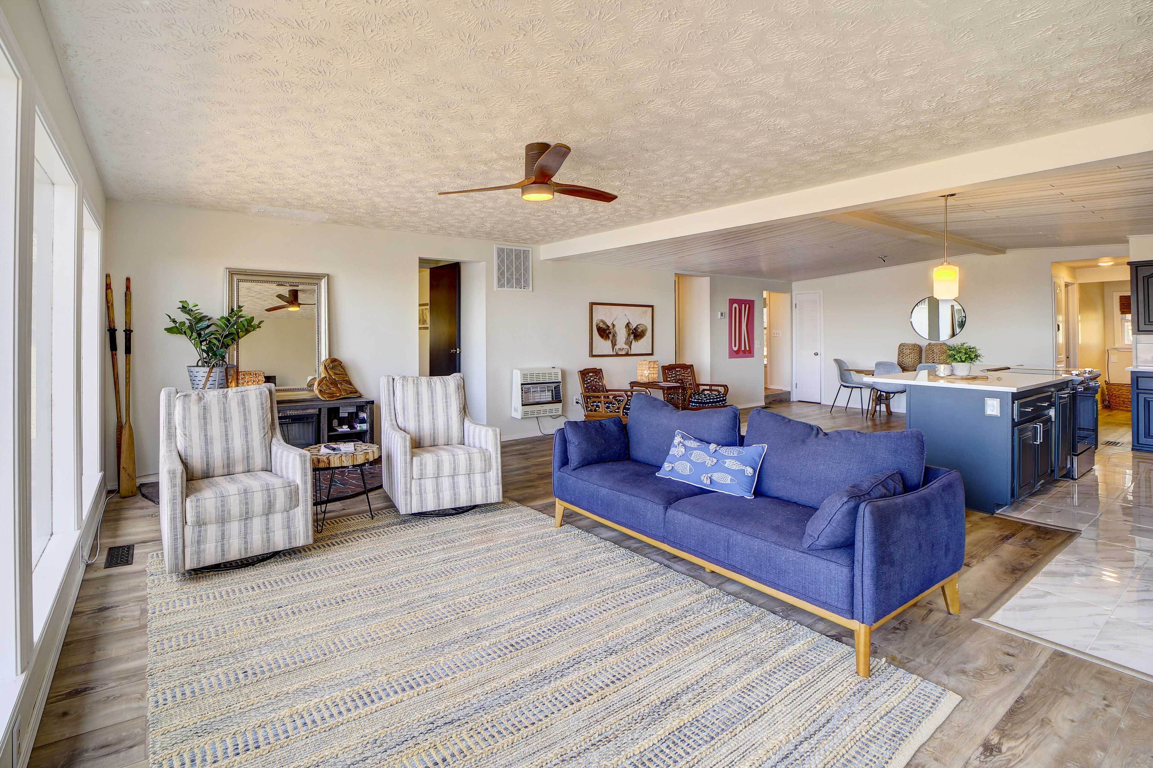 A spacious living area with a blue sofa, striped armchairs, and a large rug.
