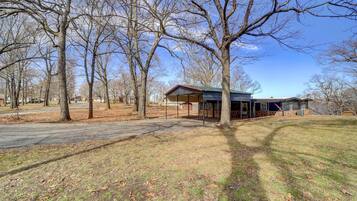 A house with a covered porch, surrounded by leafless trees and a clear sky.