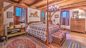 A rustic bedroom with a four-poster bed, wooden beams, a horse wall decoration, and a large window with checkered curtains. - 10 Mi to Hot Springs Natl Park: Home w/ Grill! (Hot Springs)
