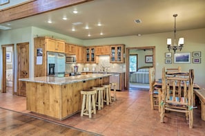 A spacious kitchen with wooden cabinets, a large island with stools, and a dining area with rustic chairs.