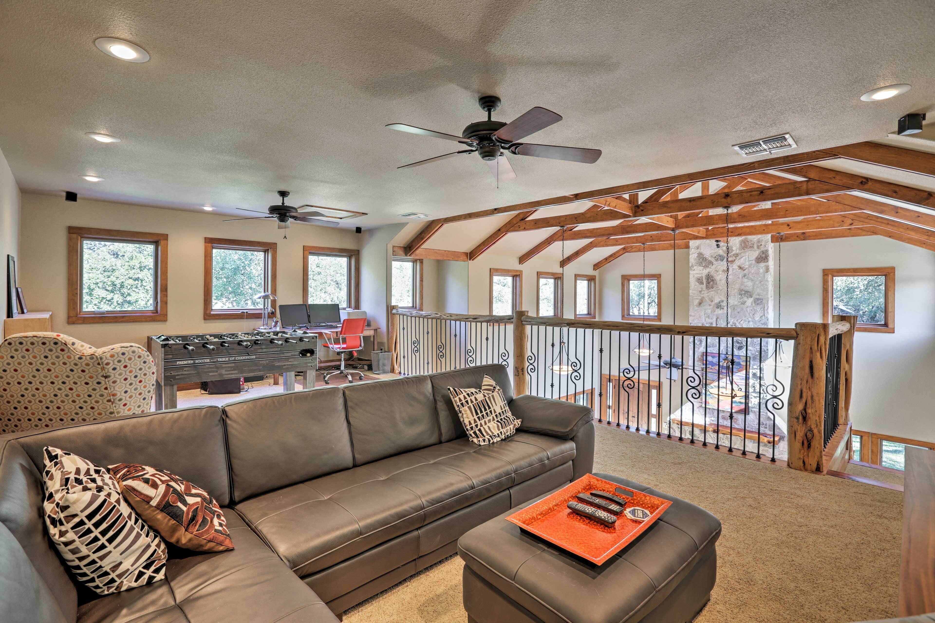 Tilava olohuone, jossa on nahkasohva, sohvapöytä, jossa on kaukosäätimet, ja parveke, jossa on kaide.