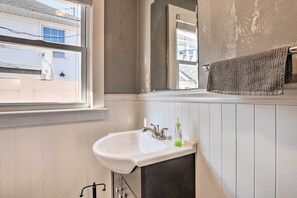 A bathroom with a white sink, dark cabinet, and a window with a view of a house. - Pet-friendly Belmar Cottage < 1 Mi to Beach! (Belmar)