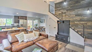 A modern living room with a brown leather sofa, a coffee table, and a staircase with a wooden wall. - Modern Hideaway: Fire Pit, 5 Mi to Mt Rainier (Mineral)