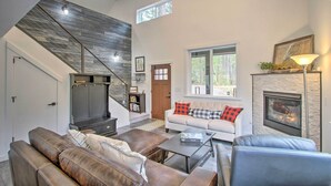 A spacious living room with a fireplace, a staircase, and a sofa with plaid cushions. - Modern Hideaway: Fire Pit, 5 Mi to Mt Rainier (Mineral)