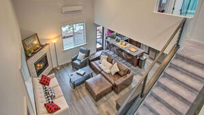 A spacious living area with a fireplace, a sofa set, a coffee table, and a dining area with a kitchen in the background. - Modern Hideaway: Fire Pit, 5 Mi to Mt Rainier (Mineral)