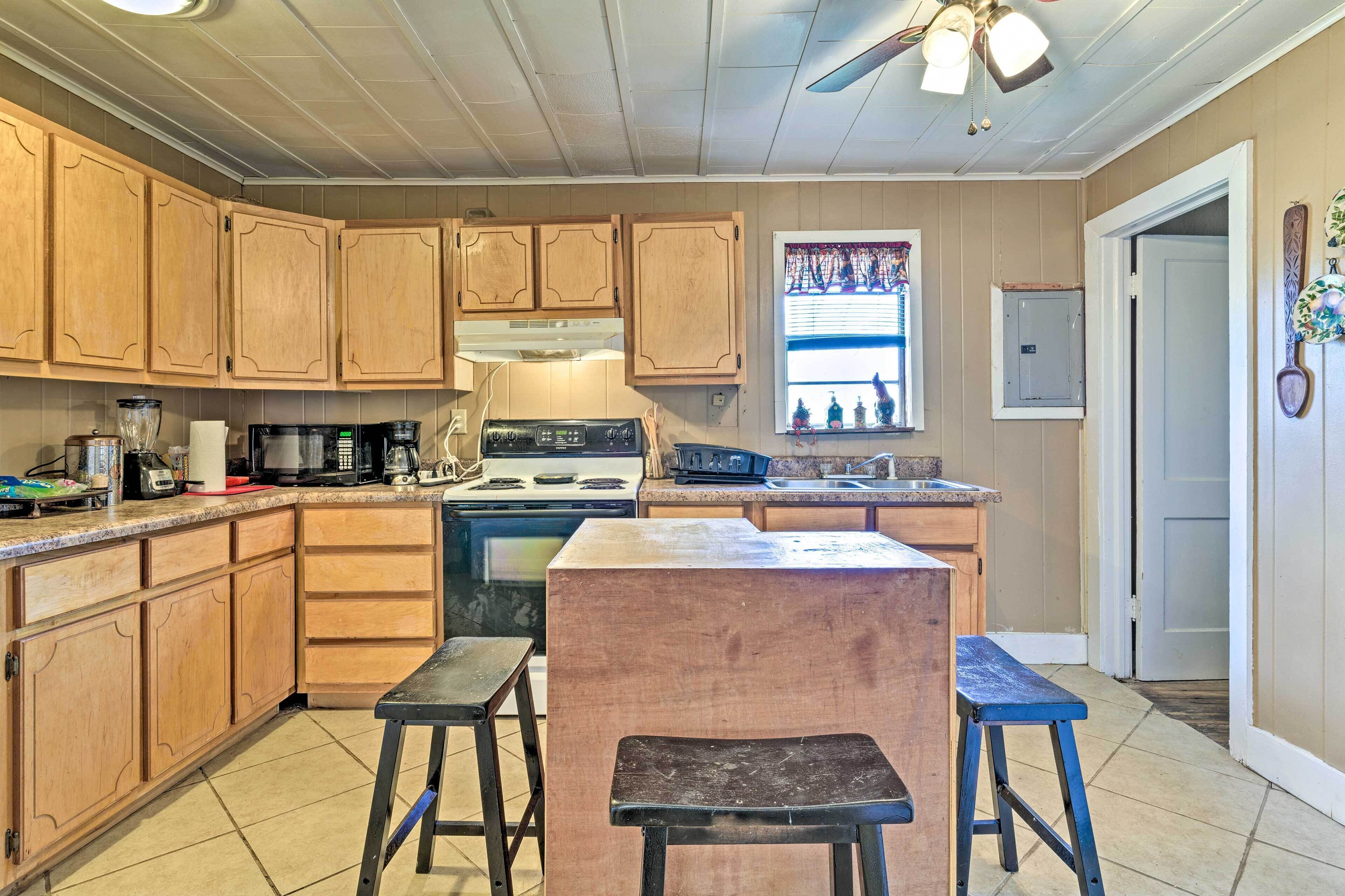 A kitchen with wooden cabinets, a stove, a microwave, and a window with decorations.
