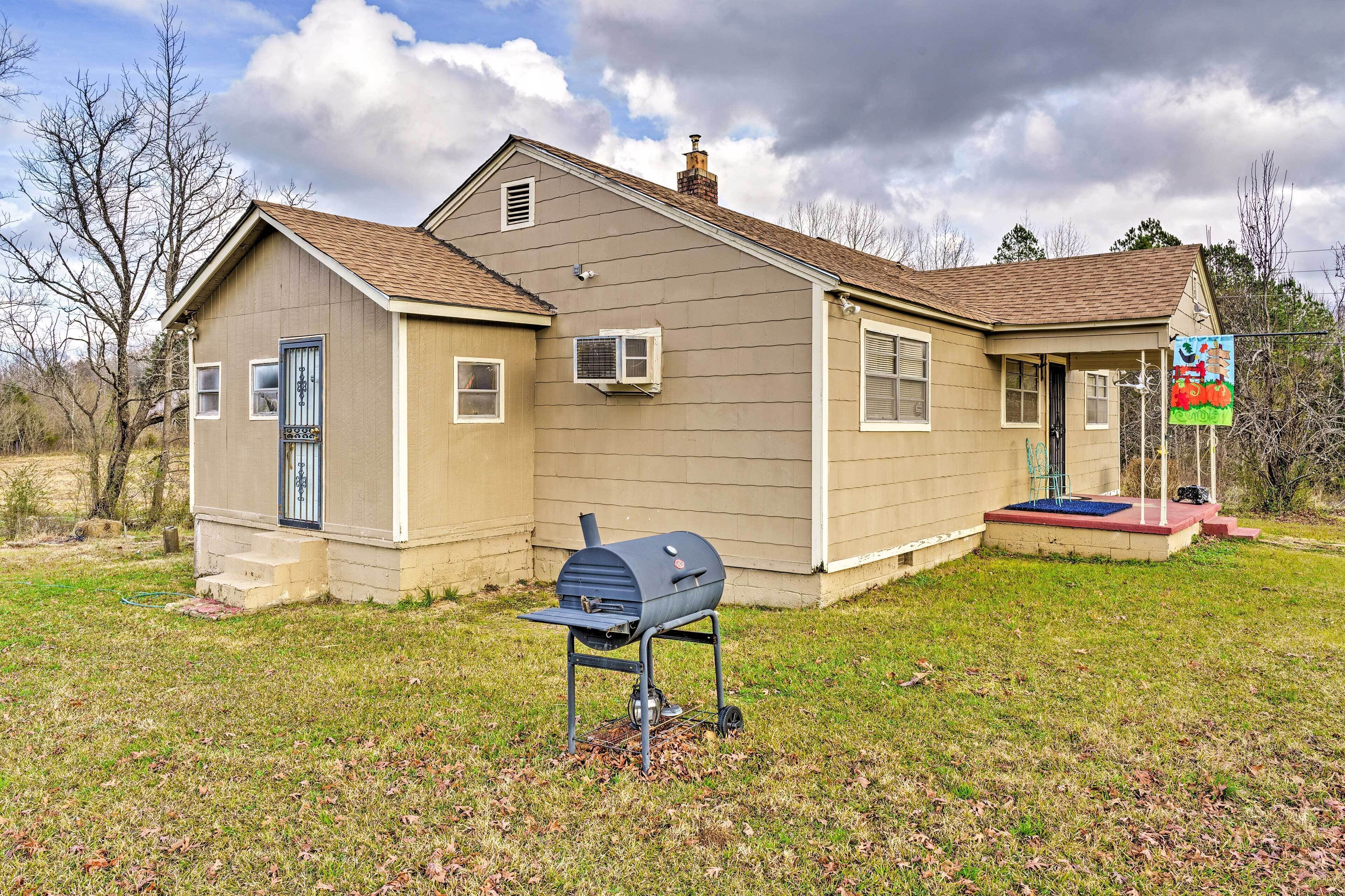 A single-story house with a front porch, a barbecue grill, and a small garden area.
