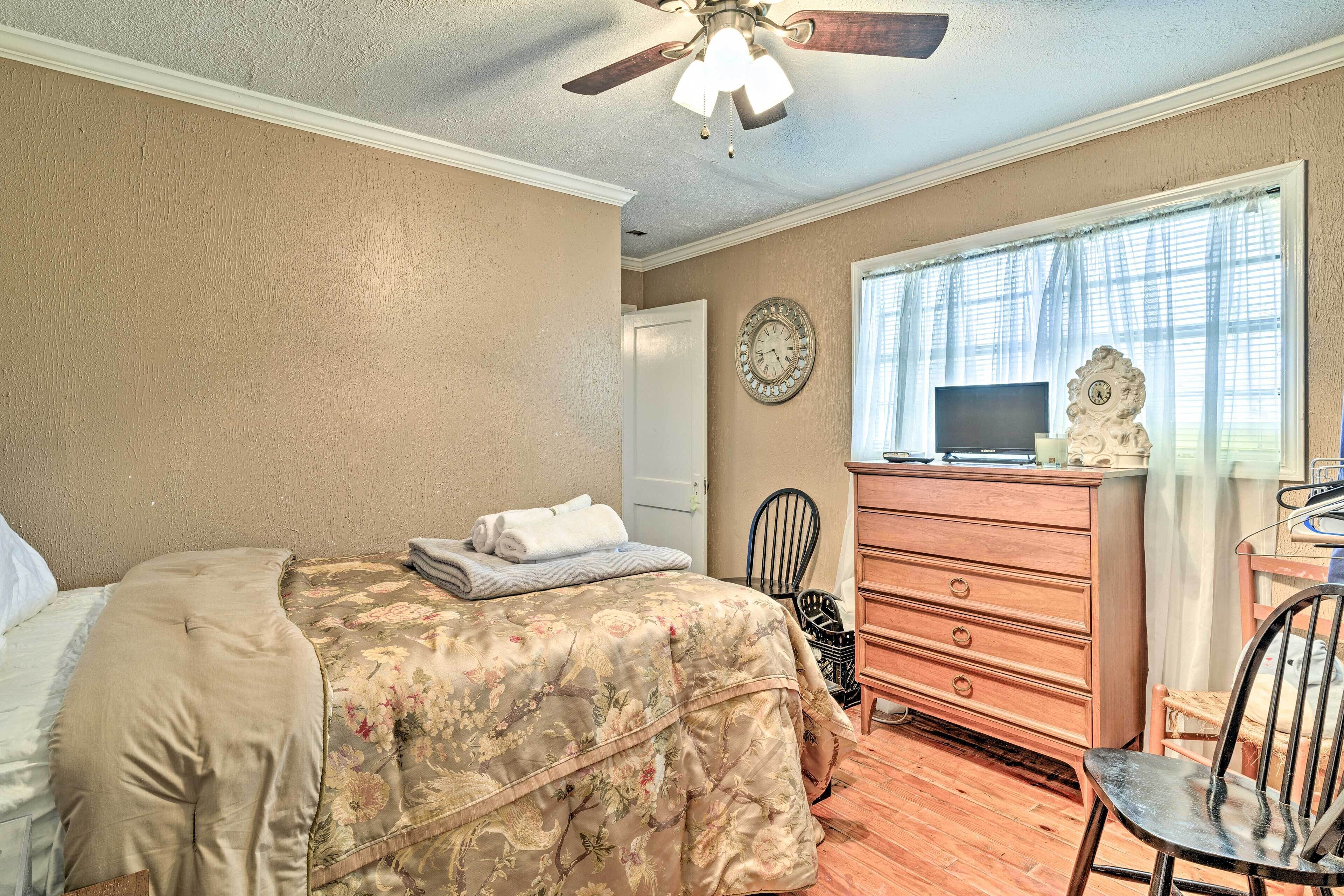 Ein Schlafzimmer mit Bett, Kommode, Stuhl und Deckenventilator.