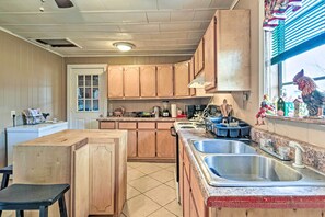 A kitchen with wooden cabinets, a central island, a sink, and a window with decorative items.