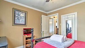 Une chambre à coucher avec un lit, une chaise en bois, un bureau et un tableau encadré au mur.
