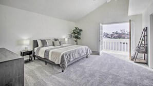 A bedroom with a bed, bedside table, lamp, and a view of the outside. - Renovated Bakersfield Home w/ Private Yard! (Bakersfield)