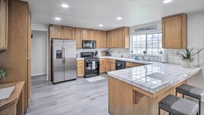 A modern kitchen with wooden cabinets, stainless steel appliances, and a tiled island. - Renovated Bakersfield Home w/ Private Yard! (Bakersfield)