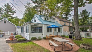 Ein Haus mit Terrasse, Grill und überdachter Sitzgelegenheit im Freien.