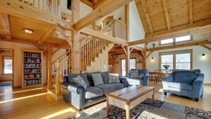 A spacious living room with a high wooden ceiling, a staircase, and a large bookshelf. - Secluded Vermont Retreat: Outdoor Pool & Deck (West Wardsboro)