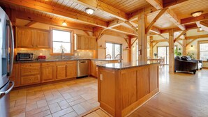 A spacious kitchen with wooden cabinets, a central island, and a dining area with a sofa and chairs. - Secluded Vermont Retreat: Outdoor Pool & Deck (West Wardsboro)