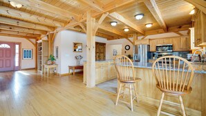 A spacious kitchen with wooden beams, a central island, and wooden chairs. - Secluded Vermont Retreat: Outdoor Pool & Deck (West Wardsboro)