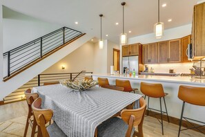 A modern kitchen with wooden cabinets, a central island, and pendant lighting. - Modern Fraser Townhome w/ Private Hot Tub & Decks! (Fraser)