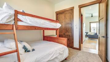 Ein Stockbett mit weißer Bettwäsche und einem Holz-Kopfteil in einem Zimmer mit beigem Teppich.