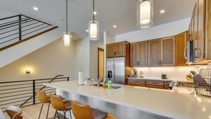 A modern kitchen with a large island, wooden cabinets, and pendant lighting. - Modern Fraser Townhome w/ Private Hot Tub & Decks! (Fraser)