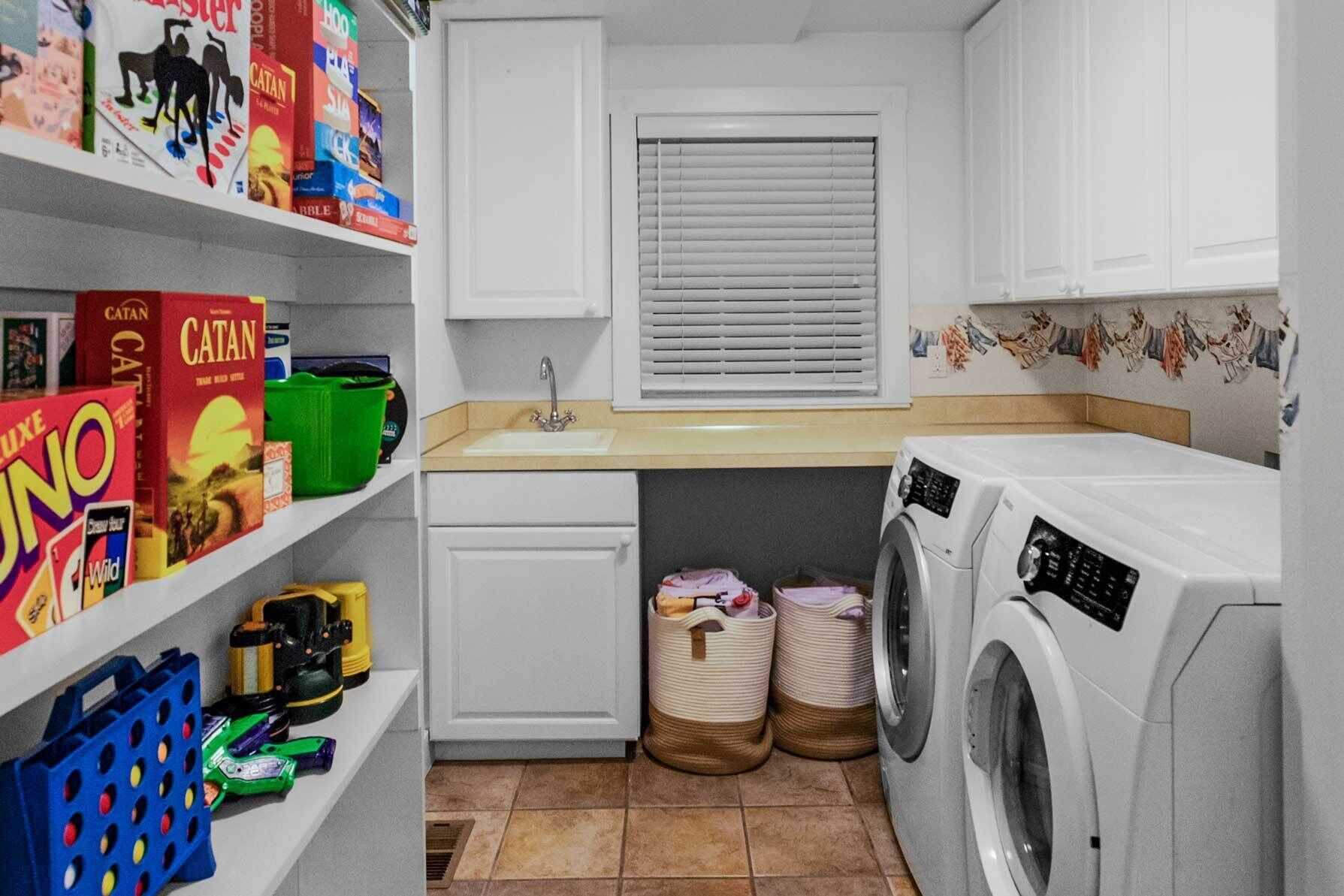 A laundry room with a washing machine, dryer, sink, and shelves with cleaning supplies.