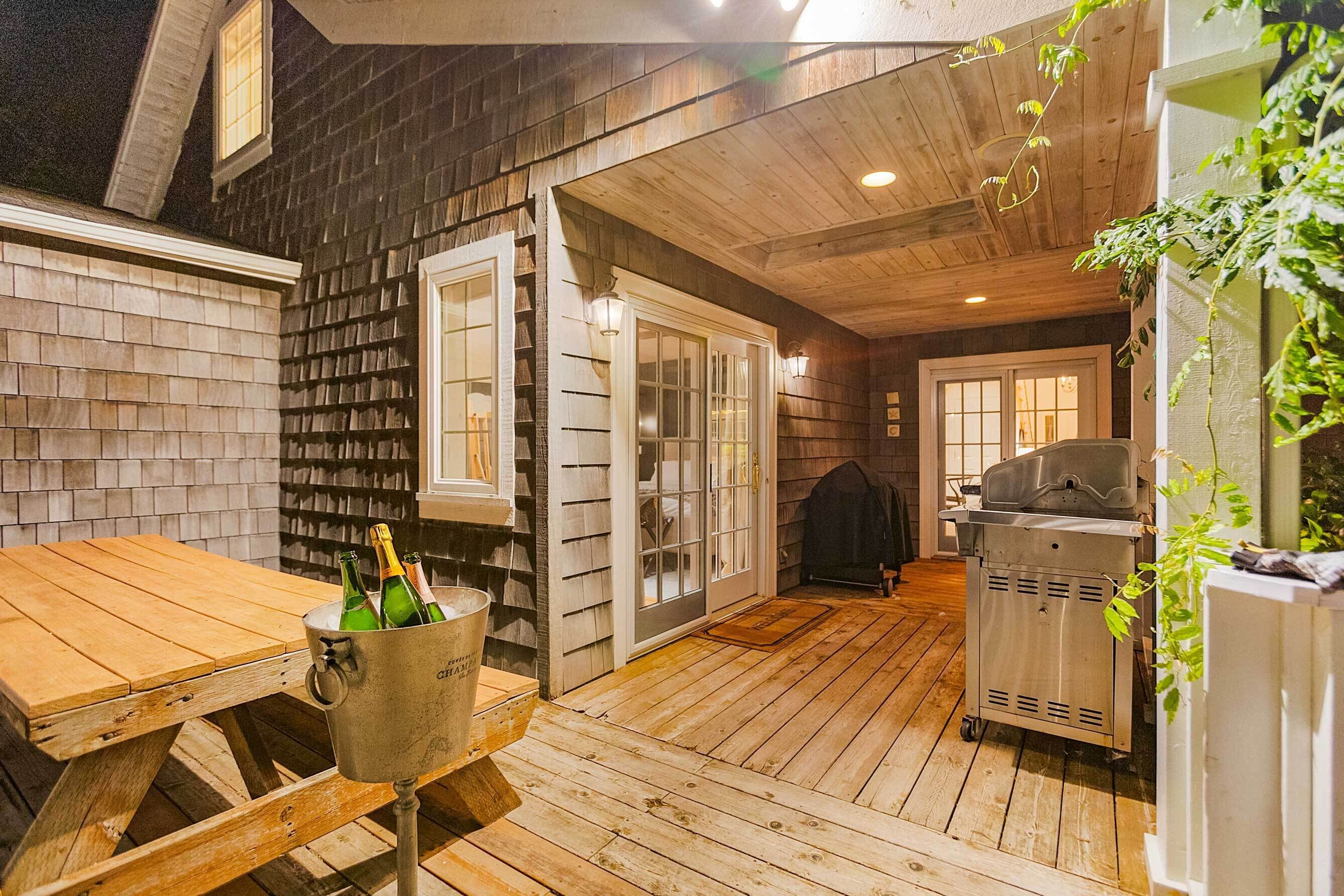 Eine Holzterrasse mit Grill und einem Eimer Champagnerflaschen.