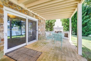 A covered patio with stone walls, a sliding glass door, and a table with chairs. - Smith Mountain Lake w/ Private Beach Only 2 People (Huddleston)