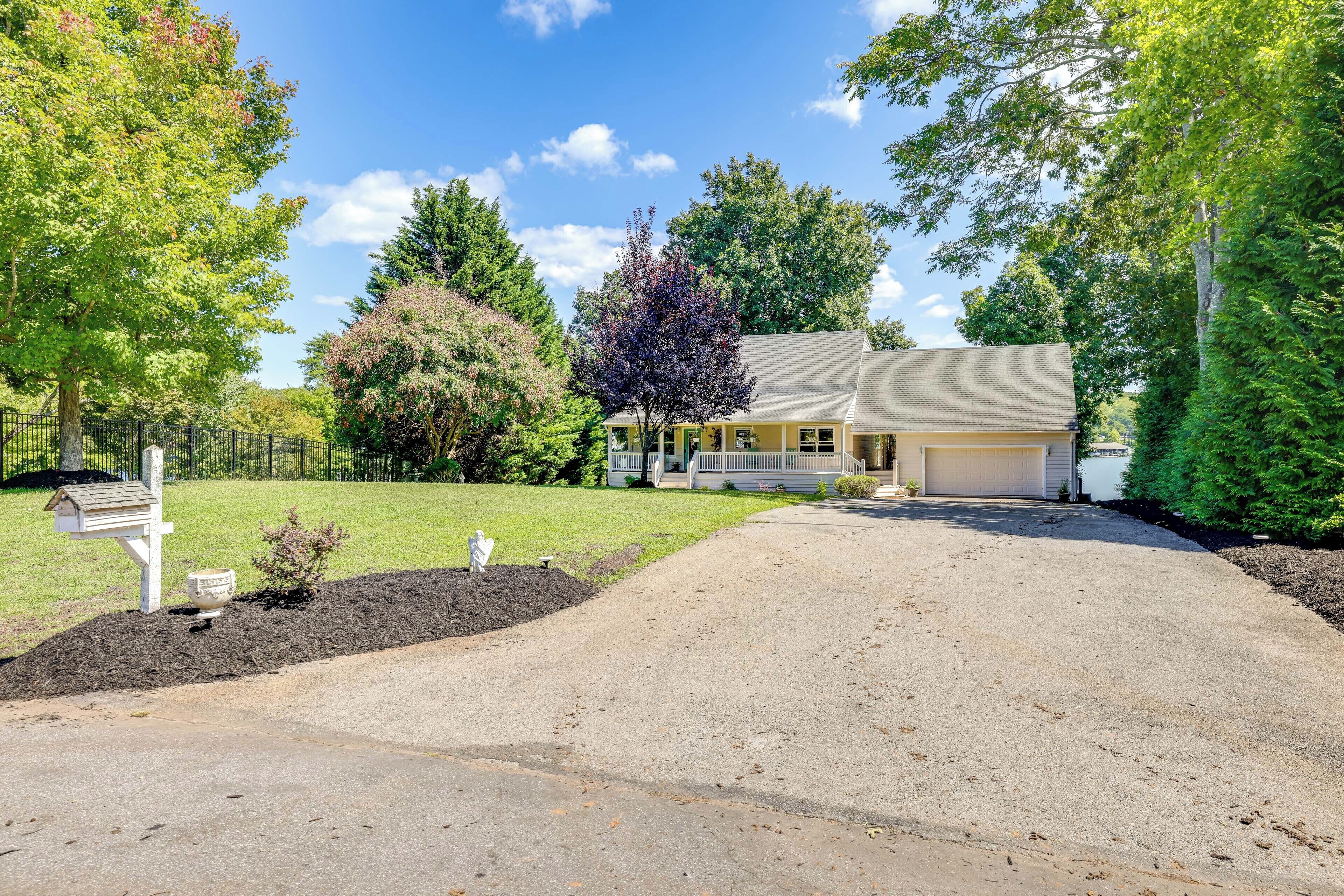 A two-story house with a front porch, a garage, and a driveway leading to the entrance.