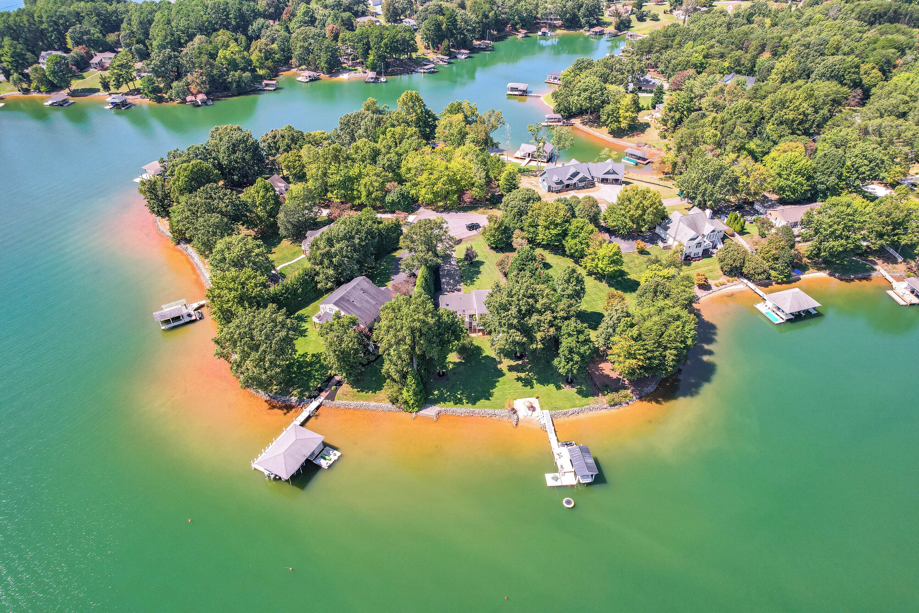 Vue aérienne d’une propriété au bord du lac, avec plusieurs maisons, des quais et des bateaux.
