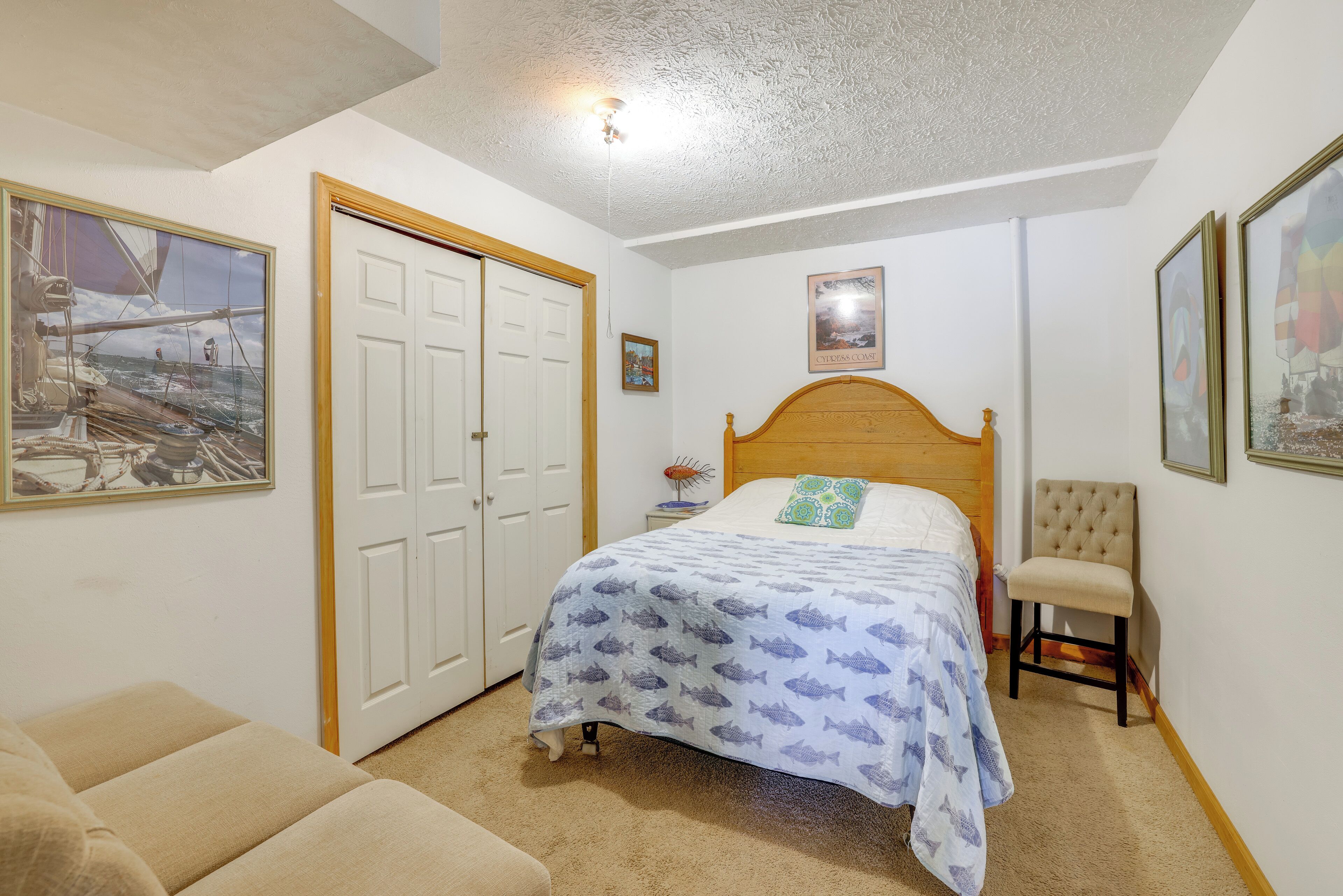 A bedroom with a bed, a chair, a door, and a ceiling light.