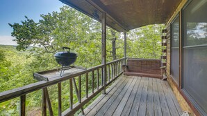 A wooden deck with a grill and a view of a forested landscape.