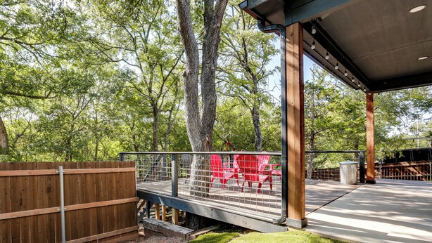 An outdoor patio area with a wooden deck, metal railing, and red chairs. - 1 Mi to Boating & Beaches: Lake Texoma Getaway (Pottsboro)