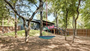 A backyard with a swing set, a covered porch, and a wooden fence. - 1 Mi to Boating & Beaches: Lake Texoma Getaway (Pottsboro)