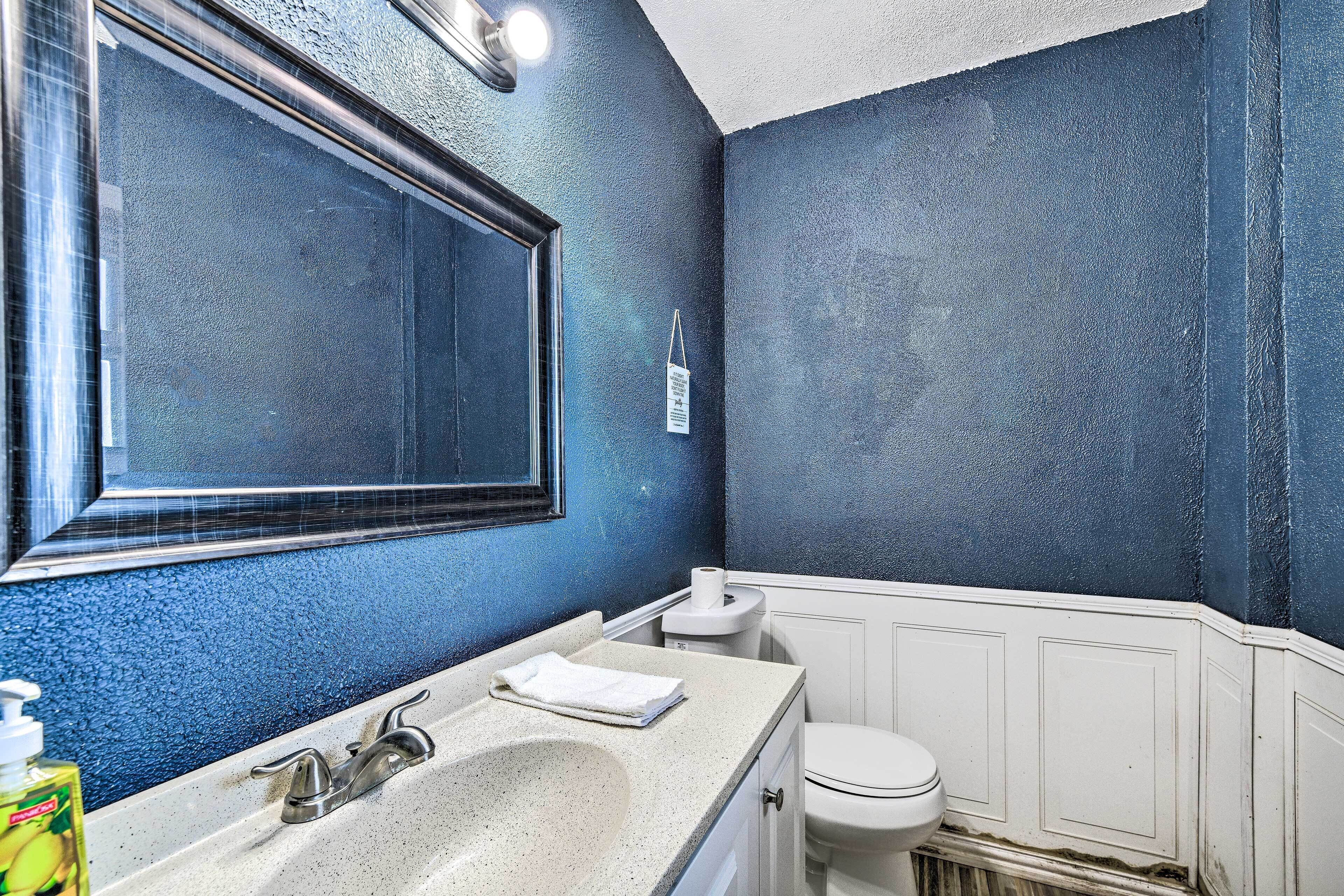A bathroom with a large mirror, a sink, and a toilet.