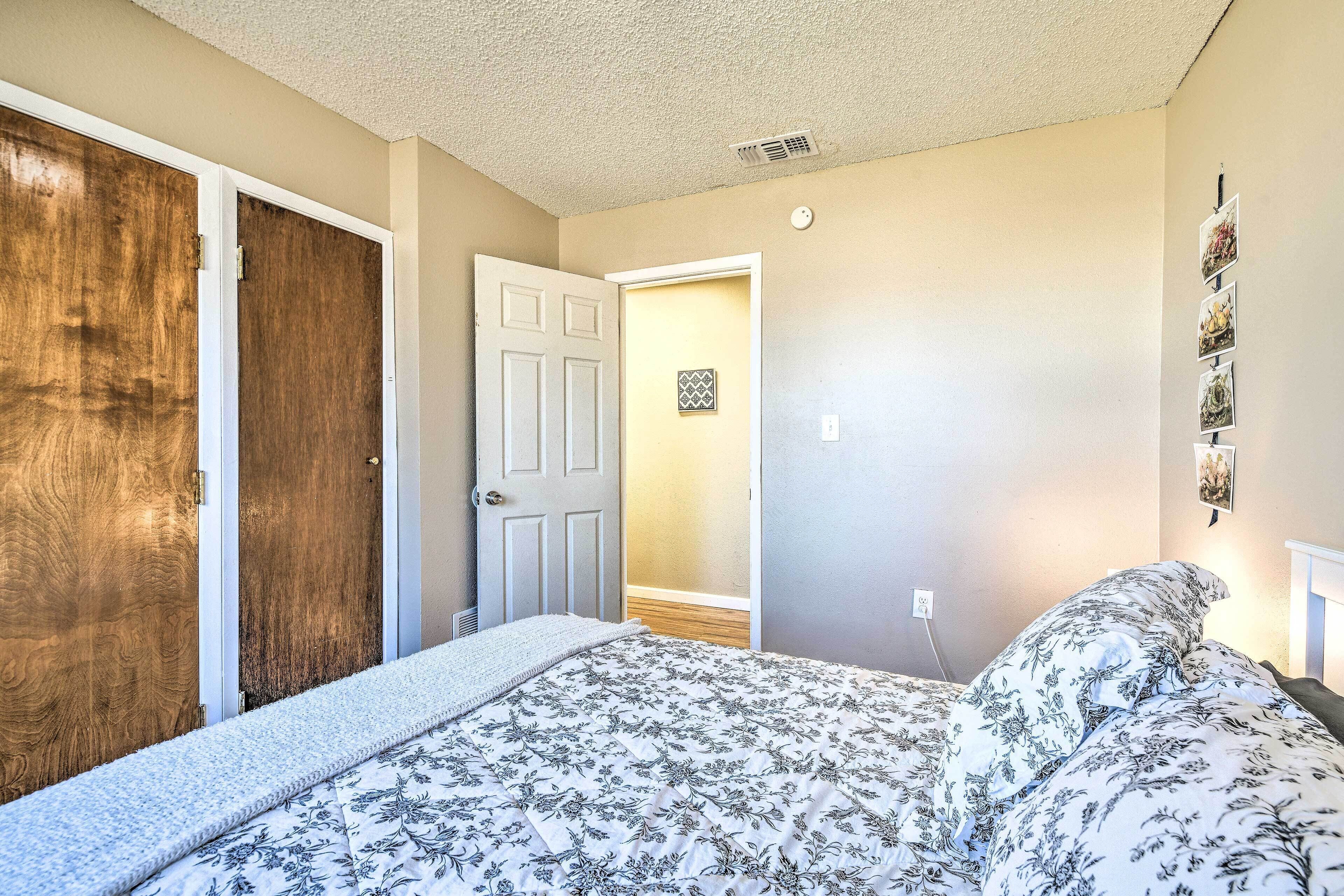 Ein Schlafzimmer mit einem Bett, einer Holztür, einer weißen Tür und einer Wand mit gerahmten Bildern.
