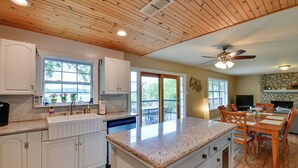 A spacious kitchen with white cabinets, a granite countertop, and a dining area with wooden furniture. - Sunny Lakefront Family Paradise w/ Deck & 2 Kayaks (Granbury)