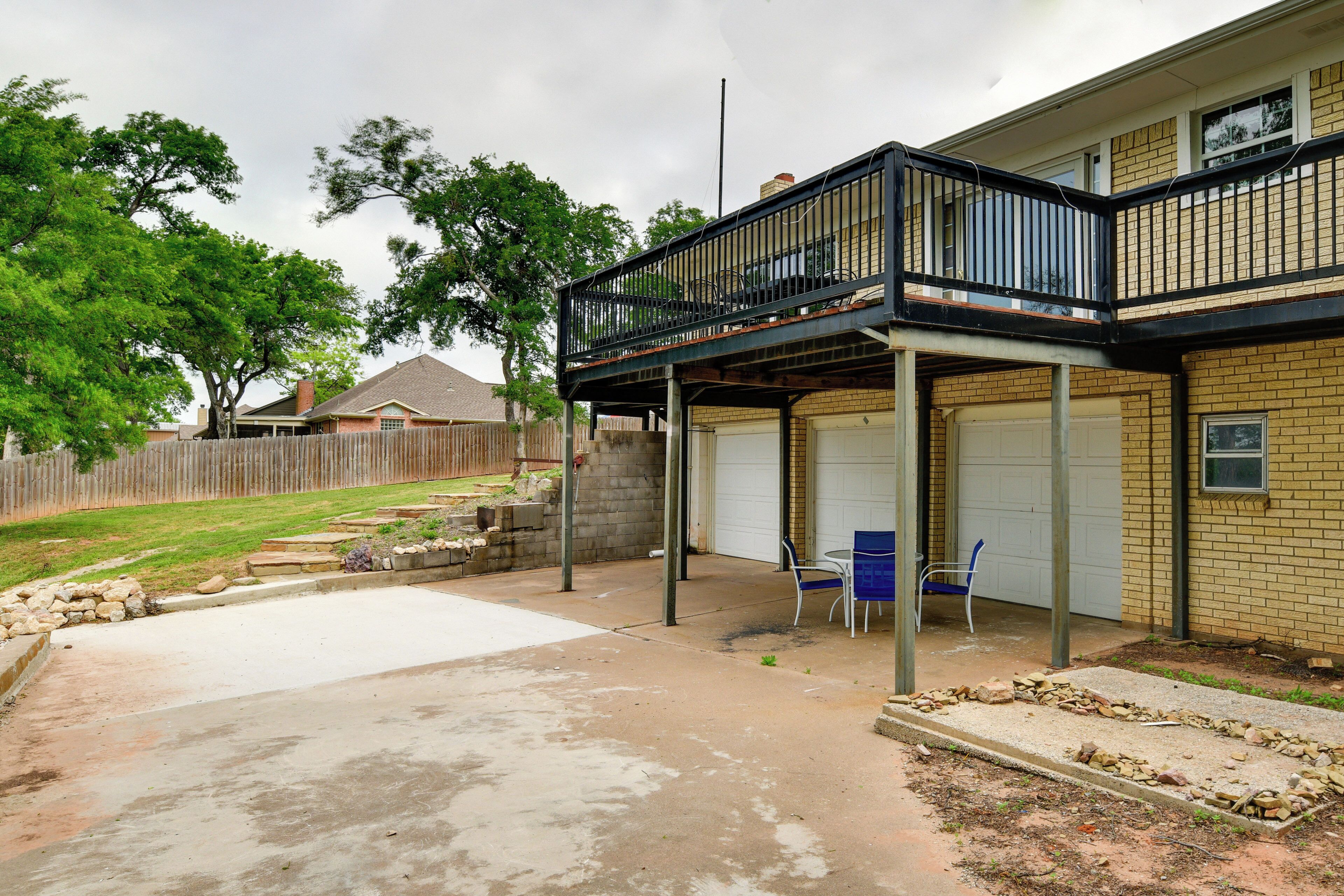 Ein Wohnhaus mit überdachter Terrasse, Garage und umzäunter Garten.