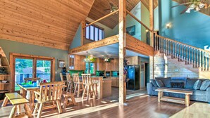 A spacious kitchen with wooden cabinets, a large island, and a dining area with wooden chairs and tables. - Waterfront Saginaw Bay Retreat w/ Grill & Yard! (Fairgrove)
